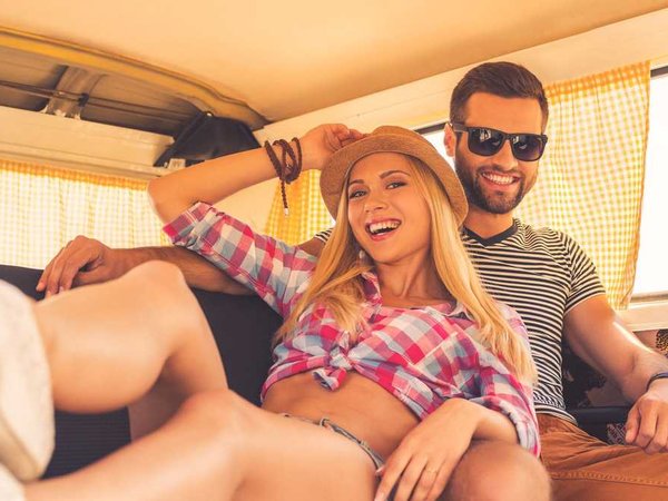 A Gen-z couple sit in the back of a van while on a road trip