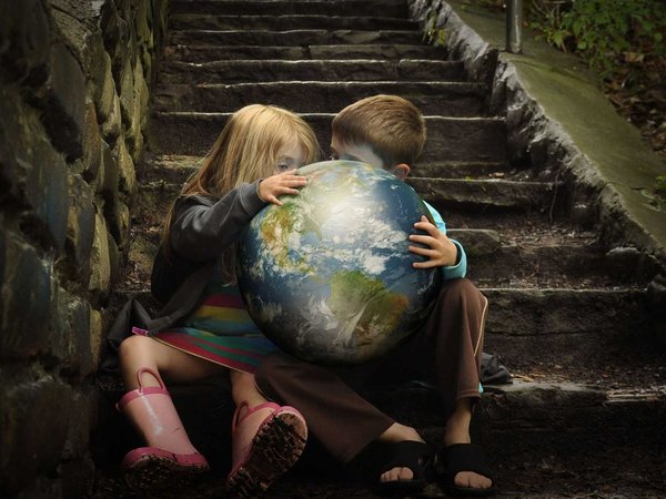 Two children studying a bright globe on a dark stairwell