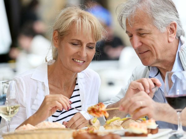 A senior couple sits down at an outdoor restaurant for healthy open air dining