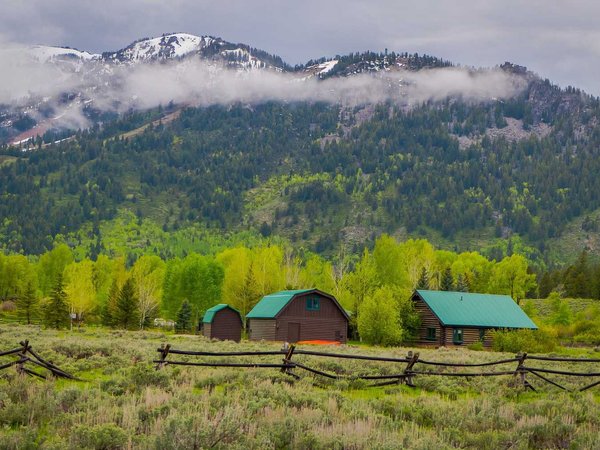 Beautiful outdoor view of wooden brown houses with green roof located in lamar valley in Yellowstone National Park, Wyoming with a mountain behind, partial covered with snow