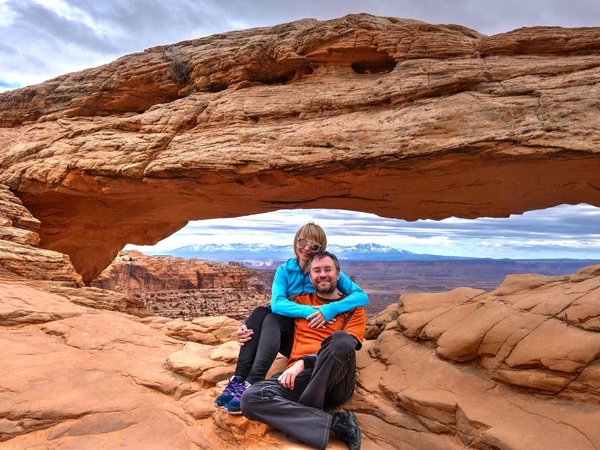 Happy friends hugging by natural arch in Canyonlands National Park. Moab. Utah. United States.