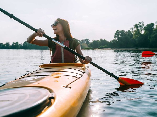 Ready for adventures. Beautiful young smiling couple kayaking on lake together