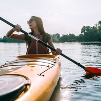 Ready for adventures. Beautiful young smiling couple kayaking on lake together
