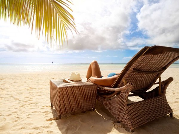 Woman on a luxury vacation in a leisurely beach-side chair.