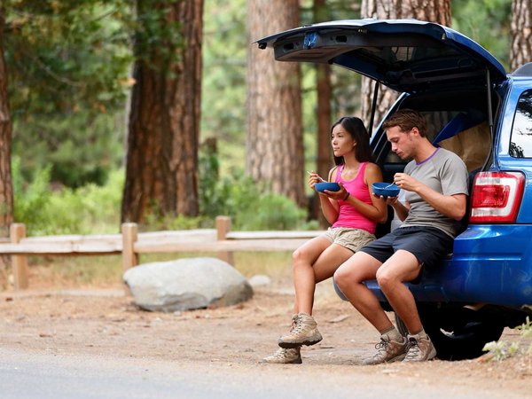 Couple on car road trip travel in eating in forest