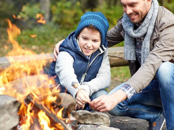 A father and his son roast marshmallows over the fire at the National Park