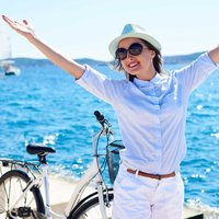 Young woman riding city bicycle near sea