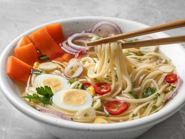 Eating noodle dish with chopsticks on table, closeup