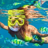 Girl in snorkeling mask dive underwater with coral reef fishes