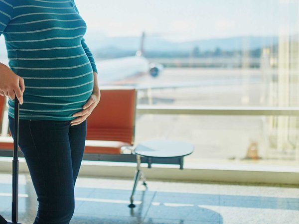 Pregnant woman waiting for flight with her luggage in an airport