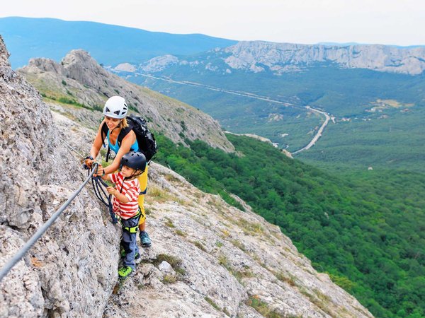 Mother, child in safety equipment climb by via ferrata route