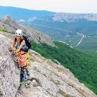 Mother, child in safety equipment climb by via ferrata route