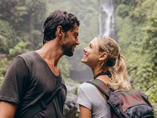 A couple pauses to enjoy the moment after a hike to a romantic waterfall