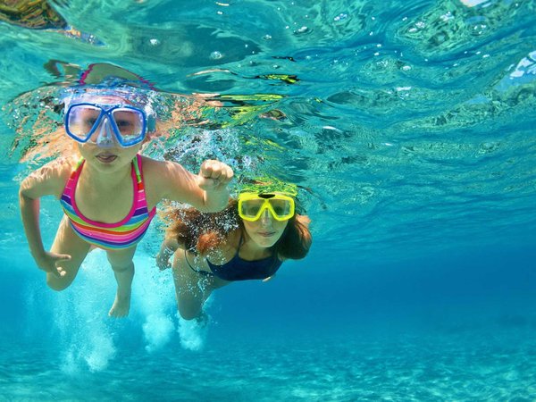 Mother with child swim underwater with fun in sea