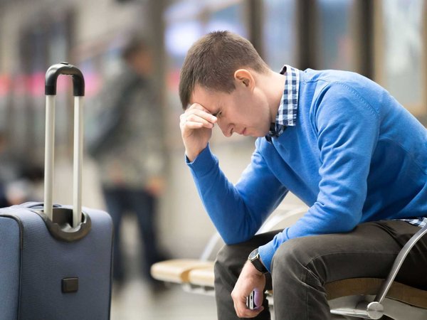 Man awaits delayed flight and contemplates the benefits of travel insurance.