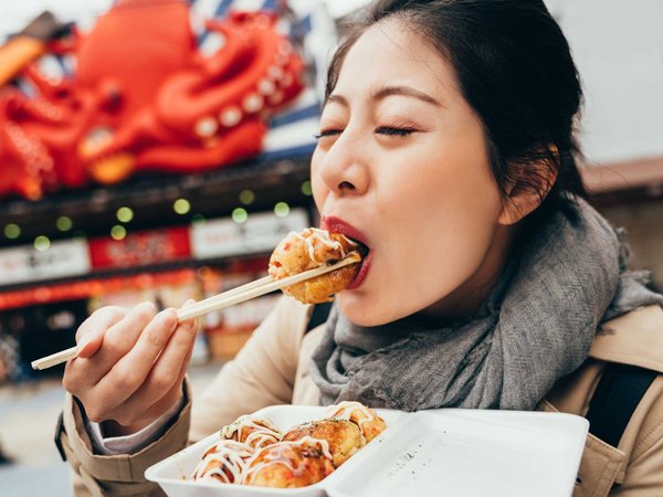 A tourist eating delicious vegetarian tacoyaki balls