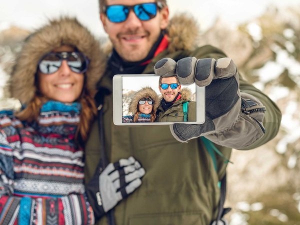 Couple takes a selfie outside in their winter coats while on vacation.
