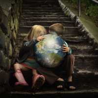 Two children studying a bright globe on a dark stairwell