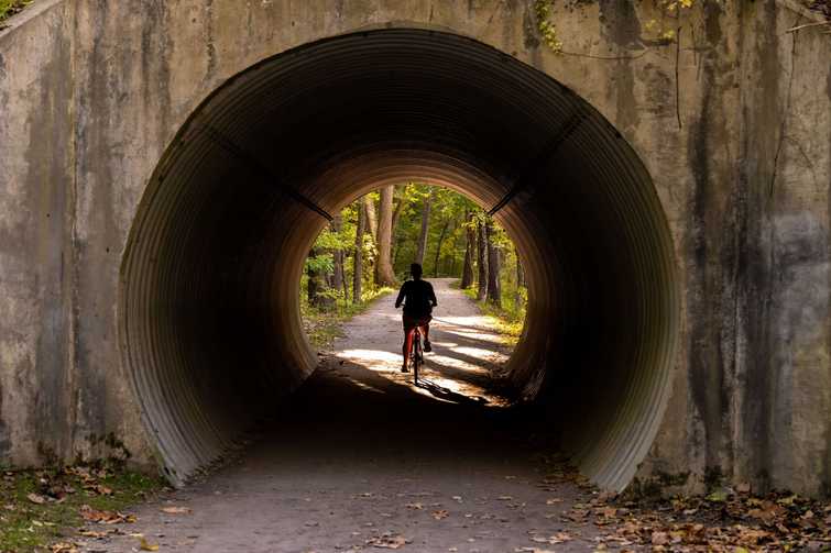 Woman Bikes Through Tunnel on Towpath