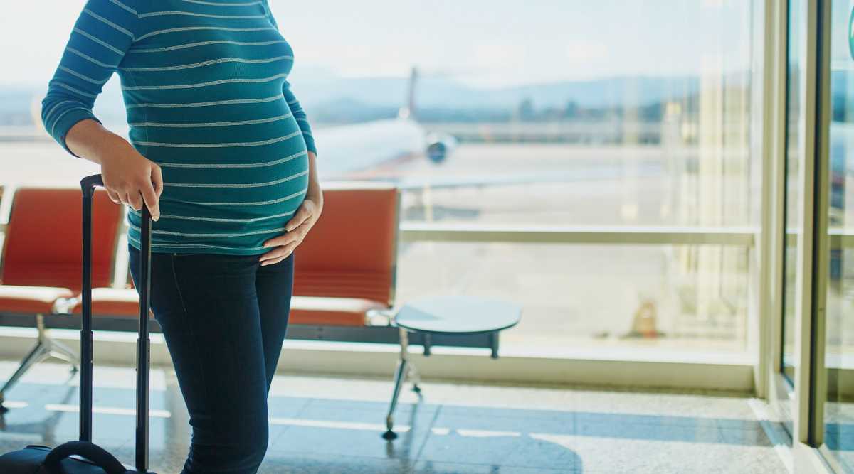 Pregnant woman waiting for flight with her luggage in an airport