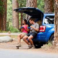Couple on car road trip travel in eating in forest