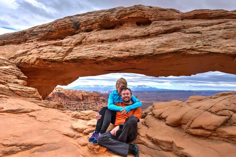 Happy friends hugging by natural arch in Canyonlands National Park. Moab. Utah. United States.