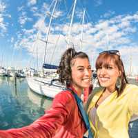 Young women girlfriends taking a selfie at harbour docks with sa