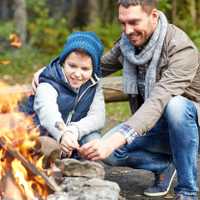 A father and his son roast marshmallows over the fire at the National Park
